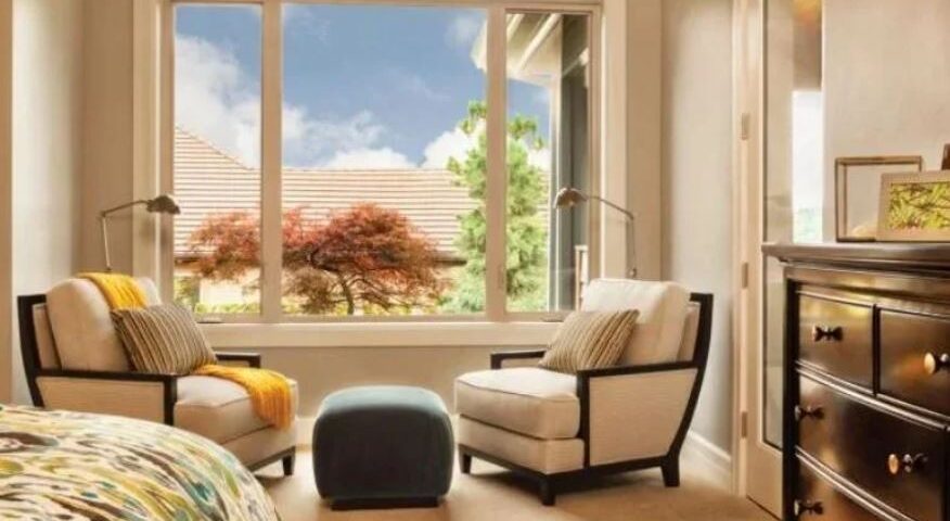 modern bedroom corner with lounge chairs facing a large window and outdoor view