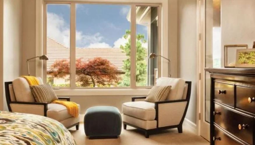 modern bedroom corner with lounge chairs facing a large window and outdoor view