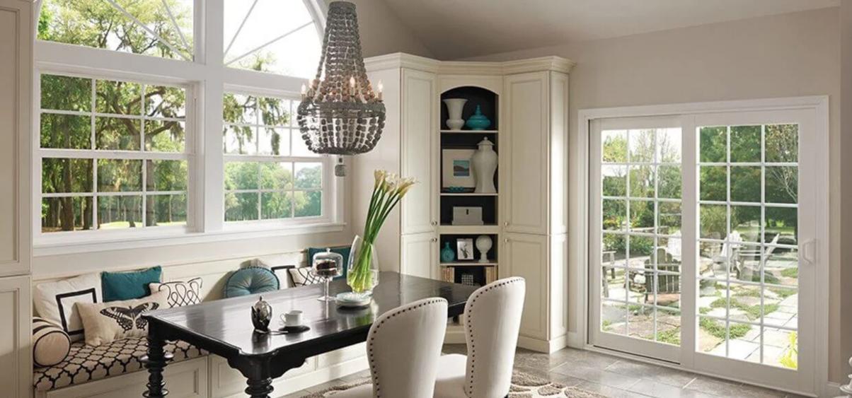 Bright dining area with large grid-style windows and French patio doors overlooking a landscaped backyard, showcasing modern replacement windows and doors Ontario, CA for improved natural light and energy efficiency.