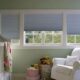 three white-framed windows with light gray shades in a nursery