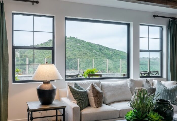Modern living room with large black-framed windows overlooking hillside landscape in Corona, CA