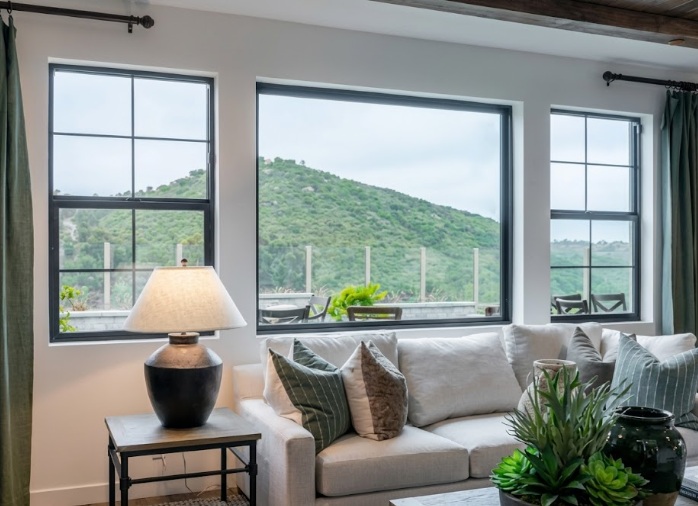 Modern living room with large black-framed windows overlooking hillside landscape in Corona, CA